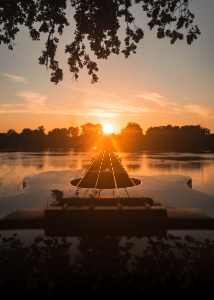 silhouette of person sitting on dock during sunset