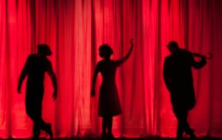 silhouette of three performers on stage