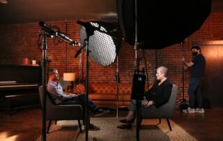 a man and a woman sitting in chairs in front of a camera