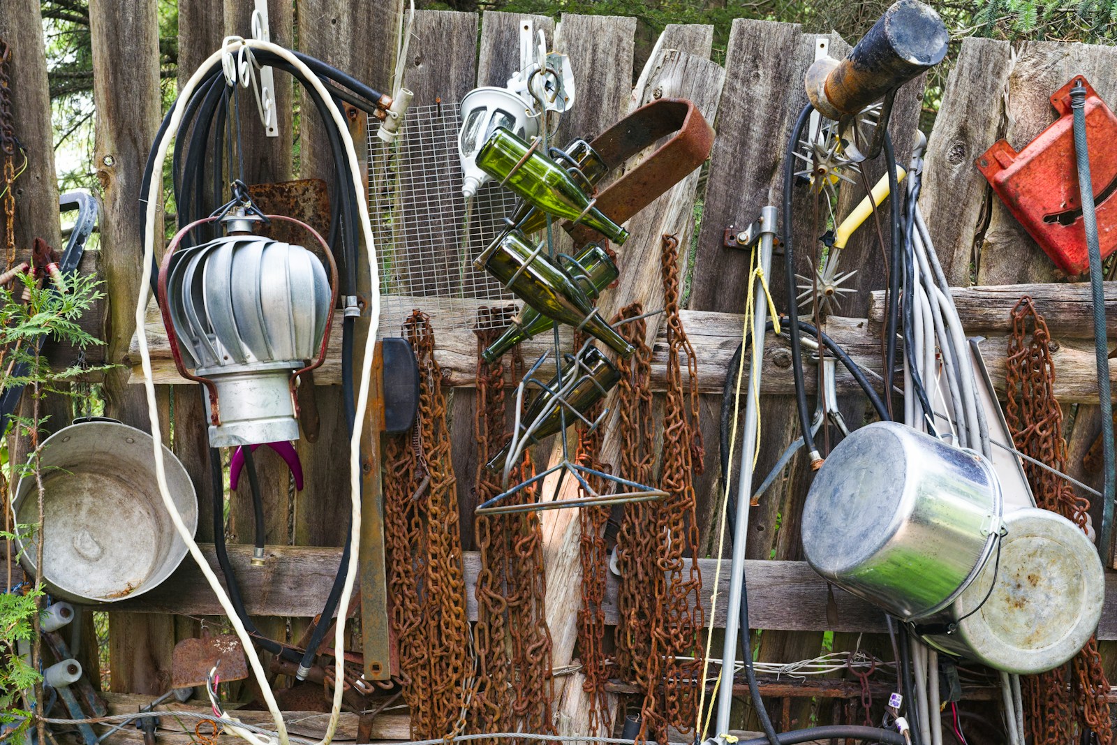 a bunch of metal pots and pans hanging on a fence